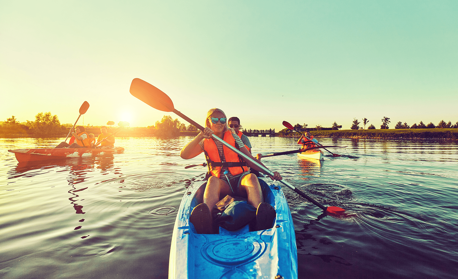 6 people kayaking in three separate kayaks during sunset